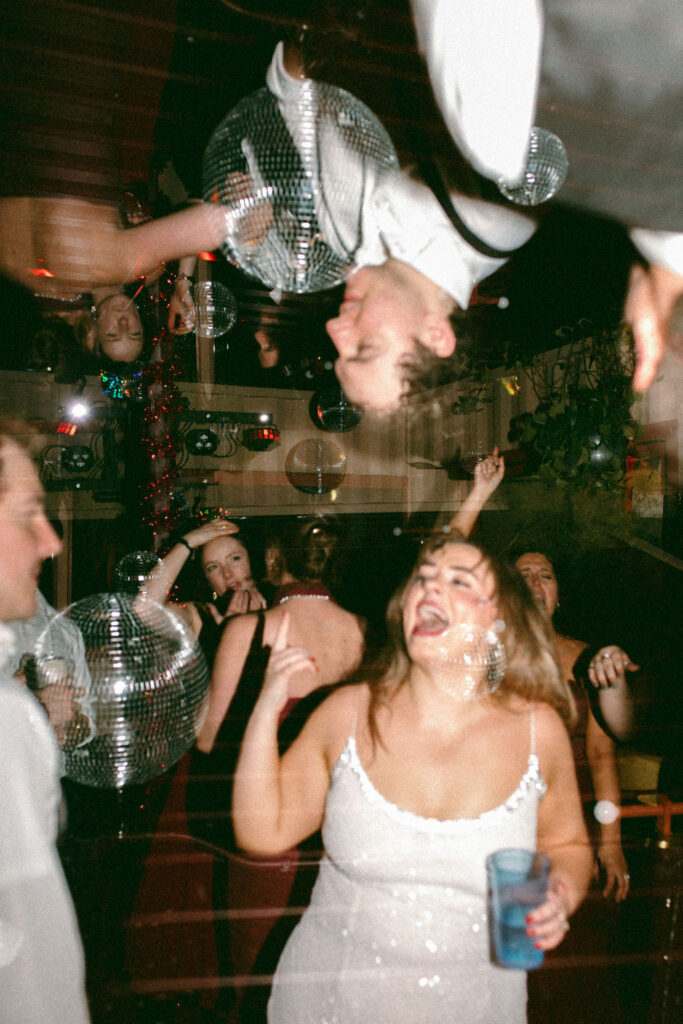 A bride & groom are photographed under a disco ball on the dancefloor of their wedding reception in an image taken by a wedding photographer pa